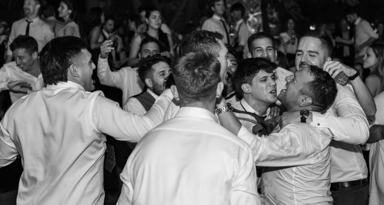 Group of men in formal attire celebrating and dancing at a party in Mendoza, Argentina.